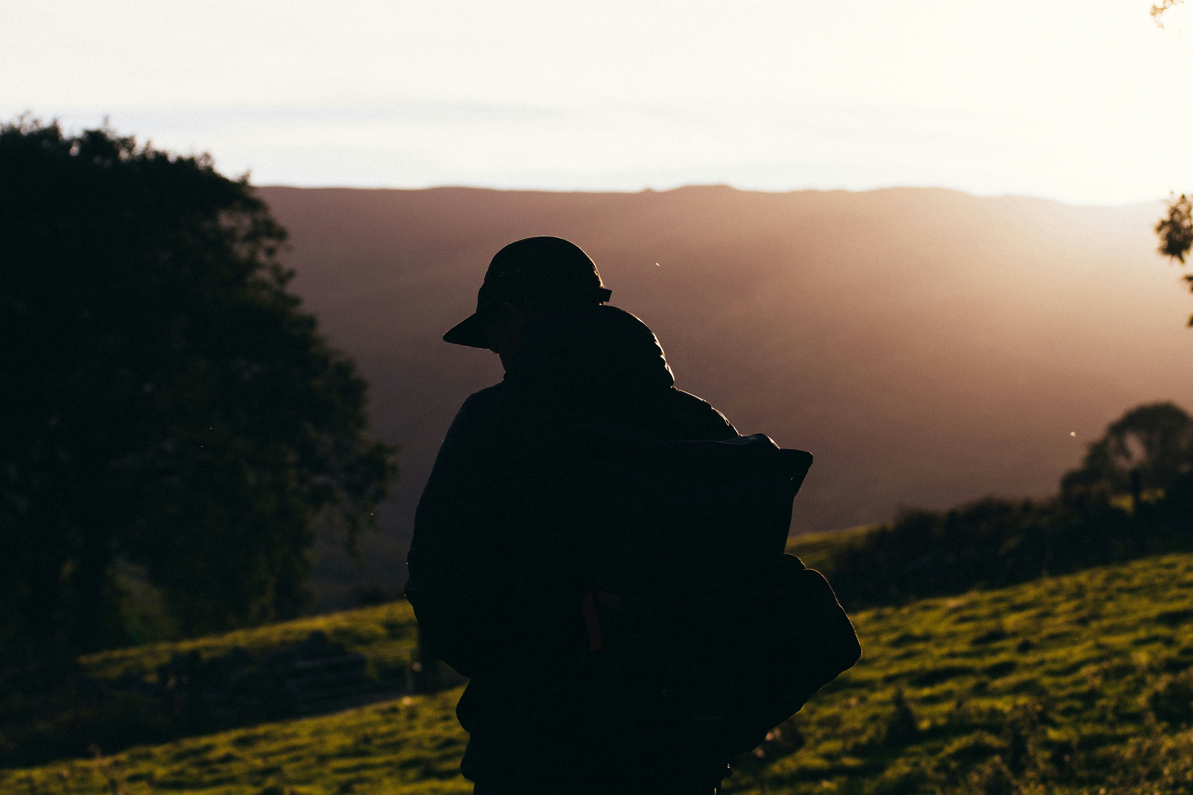 silhouette photo of person carrying backpack during daytime